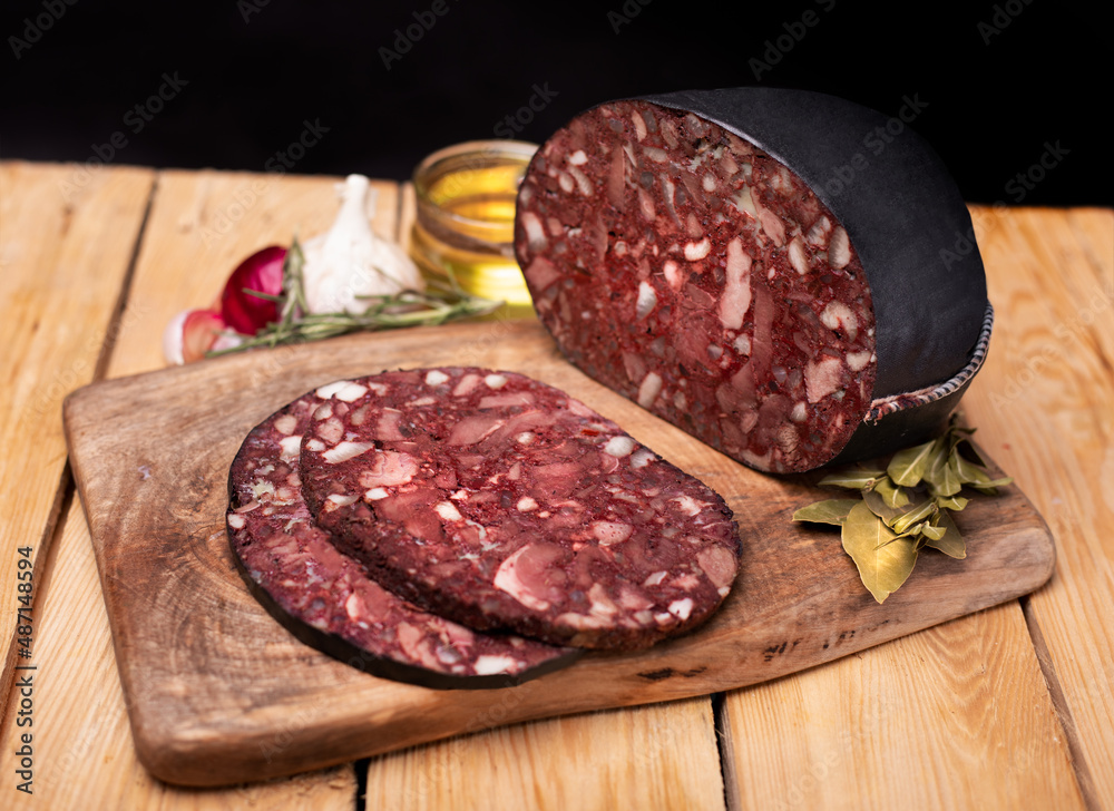 Black brawn, blood sausage, black pudding on a wood cutting board, close up. Polish cold cuts, meat products. Black brawn, blood sausage, black pudding on a wood cutting board, close up. Polish cold cuts, meat products.