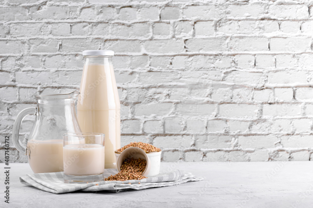 Φωτογραφία Vegan non diary buckwheat milk in bottle, in jug and glass with buckwheat groats in a bowl and on white stone table