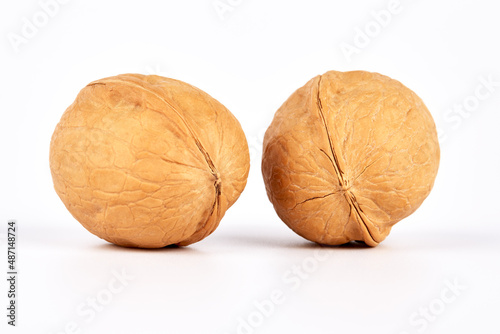 Two whole inshell walnuts on a white background