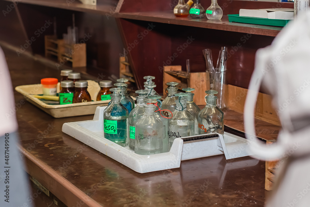 Glass bottles and test tubes in the chemical laboratory of the University. They stand on a brown table.