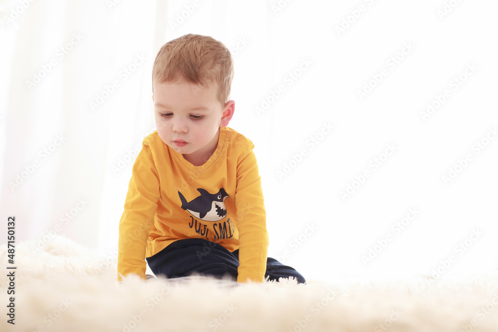 3 year old child sitting on a white fluffy blanket in a white room and looking at a book happily
3 year old child sitting on a white fluffy blanket in a white room and looking at a book happily