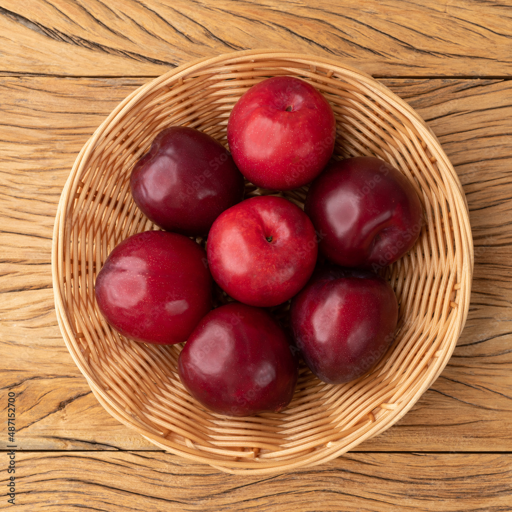 Plums in a basket over wooden table Plums in a basket over wooden table