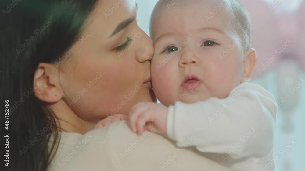Closeup to the camera details of a beautiful baby in the mommy s arms in the morning hugging with love and spending a good time together Closeup to the camera details of a beautiful baby in the mommy s arms in the morning hugging with love and spending a good time together