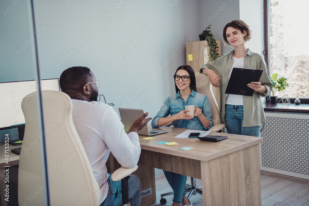 Fototapeta premium Photo of cheerful happy agents sitting table working discussing last news smiling indoors workplace workstation