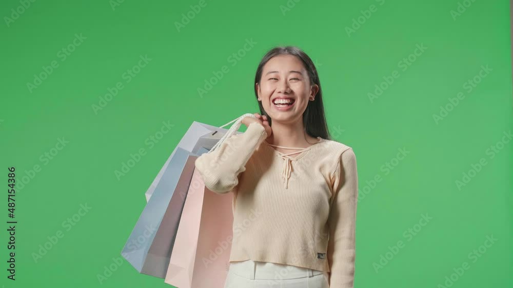 An Asian Shopping Woman Holding Shopping Bags Up Being Happy And Smiling To Camera While Standing In Front Of Green Screen
An Asian Shopping Woman Holding Shopping Bags Up Being Happy And Smiling To Camera While Standing In Front Of Green Screen