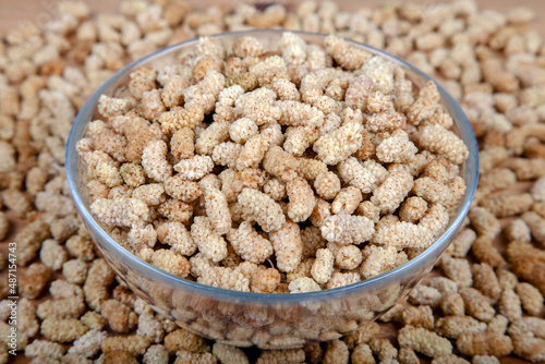 Dried white mulberry in glass bowl on wooden background