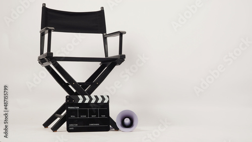 Black director chair and black clapper board with yellow megaphone on white background