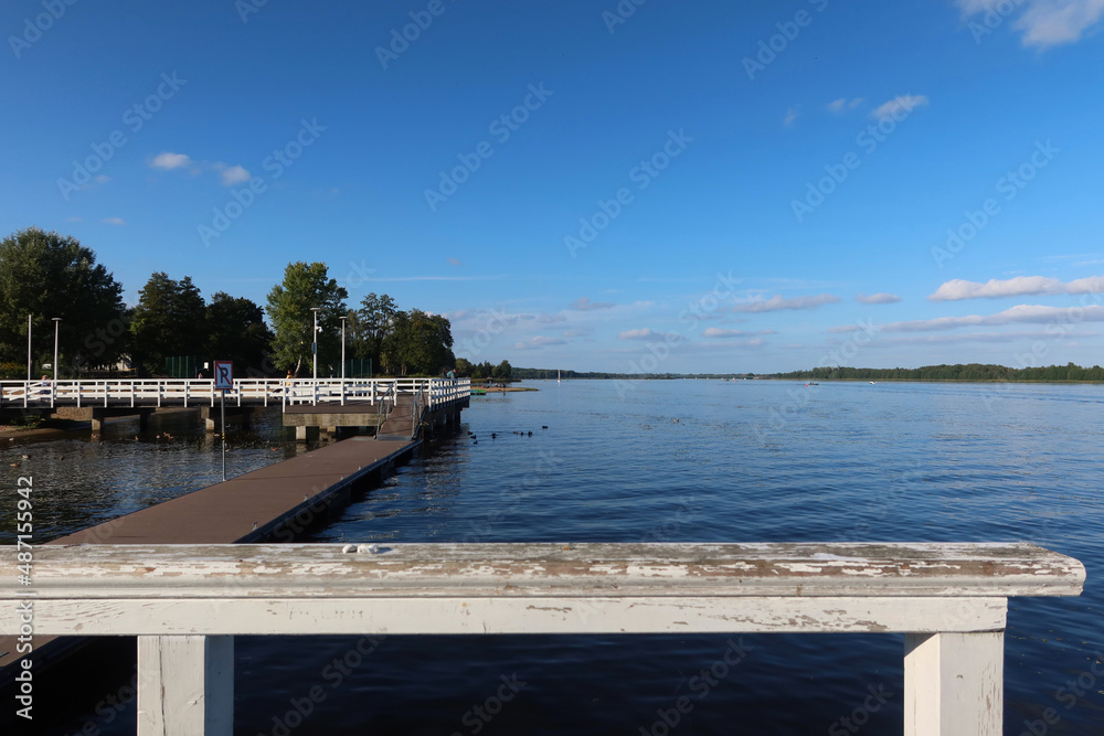 Fototapeta premium Narew river in Serock town, Mazovia, Poland. White pier at Narew river in Serock. Next to the beach.