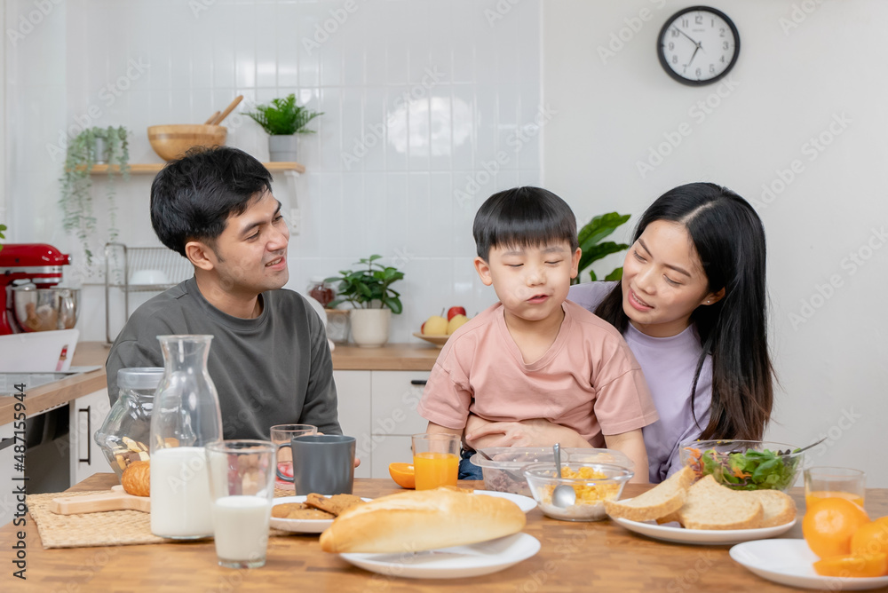 happy family together. Asian parent eating breakfast with little son in the kitchen. happy family together. Asian parent eating breakfast with little son in the kitchen.