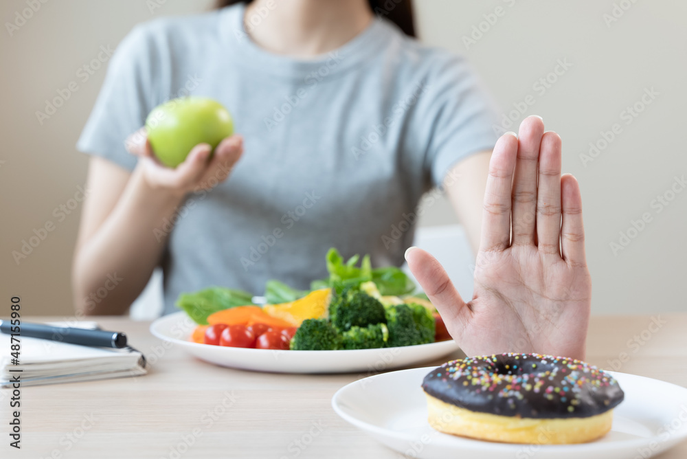 Woman on dieting for good health concept. Close up female using hand push out her favourite donut and choose salad vegetables for good health. Woman on dieting for good health concept. Close up female using hand push out her favourite donut and choose salad vegetables for good health.