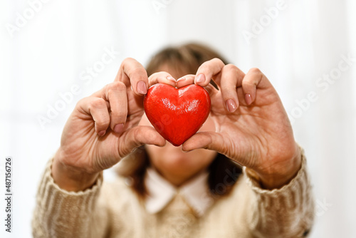 Fototapeta Naklejka Na Ścianę i Meble -  Red heart in women's hands close-up.
