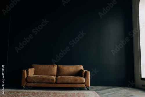 Luxurious loft interior. brown leather sofa in a dark room. Spacious room with space for text