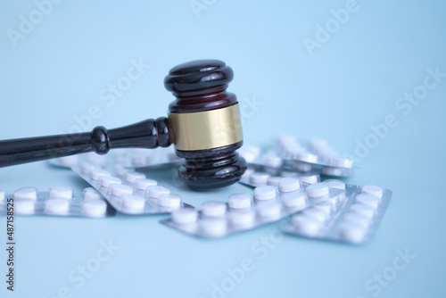 Gavel and pills on a blue background. Medical crime. Judge gavel and pills. Litigation Medicine-Related Healthcare in Pharmaceuticals. Law in medicine