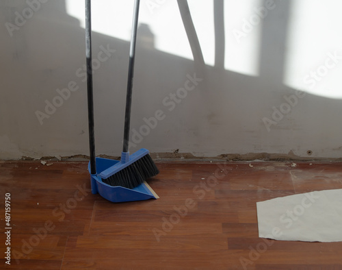 Cleaning of construction debris.Renovation in a residential building.Dustpan and brush for garbage collection.Dusty floor and torn wallpaper.