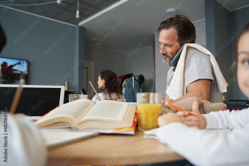 Obraz premium Man talking on phone from home while working at table