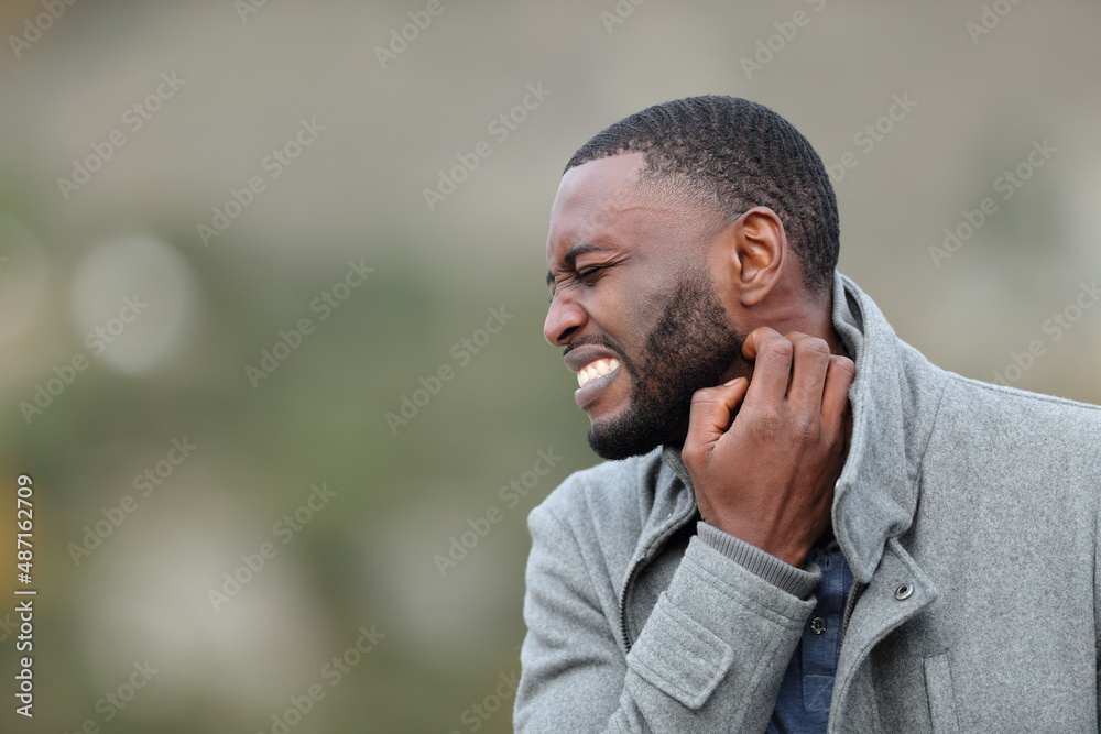 © PheelingsMedia - Stressed man with black skin scratching neck in winter