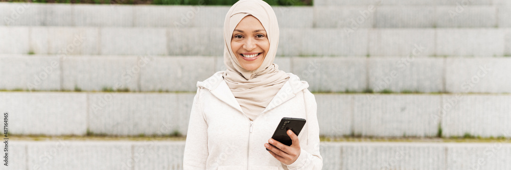 Middle eastern woman in hijab using mobile phone while working out Middle eastern woman in hijab using mobile phone while working out