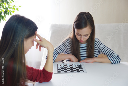 Board game of checkers. Girls play checkers at home in a bright room