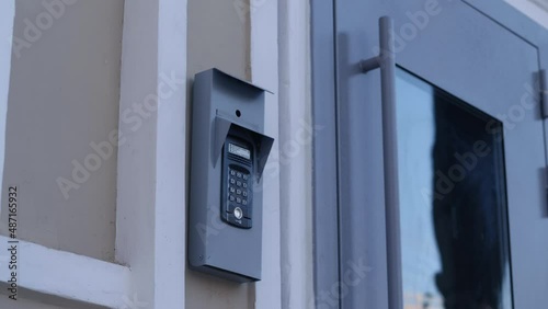 House intercom on wall and closed door with glass reflecting sky at contemporary building entrance on city street close view photo