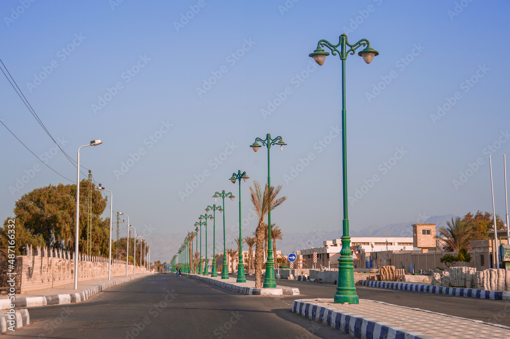 wide open avenue with street lamps extending into the horizon to the sea