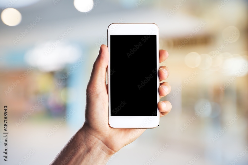 Human hand holding phone with blank screen and cityscape blur background