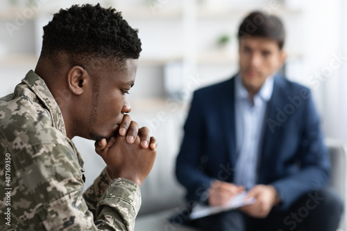 Pensive black soldier having conversation with social worker photo