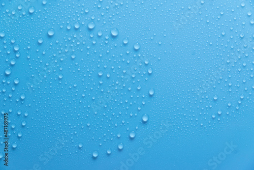 Blue pastel water drops on light shiny surface