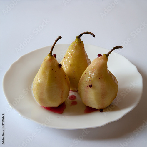 In the plate is a pear poured with syrup. On white background.