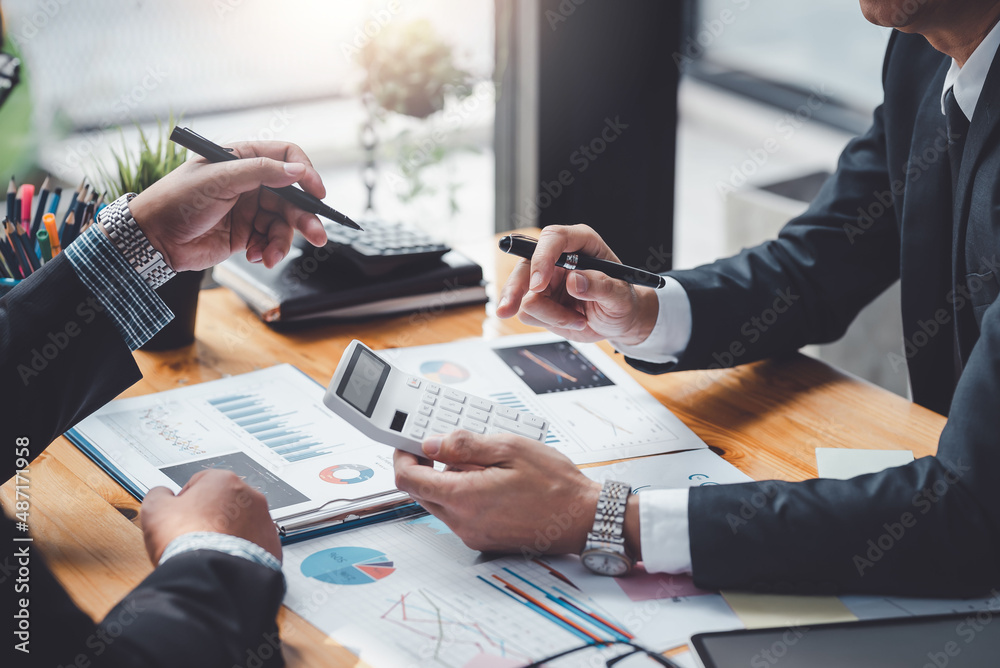 Business people using a calculator Think analyzing income, financial statements, balance sheet, company information. - obrazy, fototapety, plakaty 