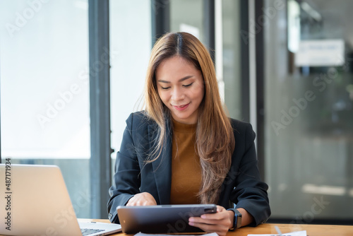 Asian businesswoman who is happy to work using a tablet.