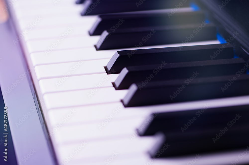 Macro photo of a piano keyboard with lens flares, small focus field on a black key in the middle Macro photo of a piano keyboard with lens flares, small focus field on a black key in the middle