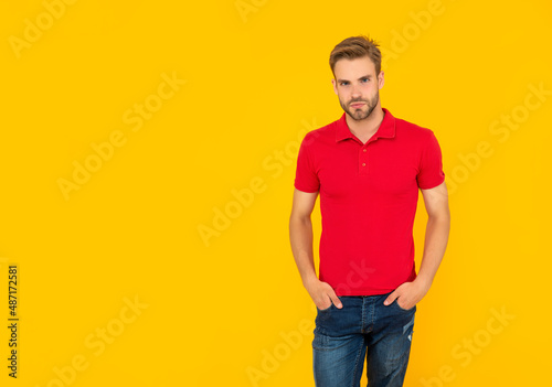 man with bristle in red shirt. young man with beard on yellow background with copy space.