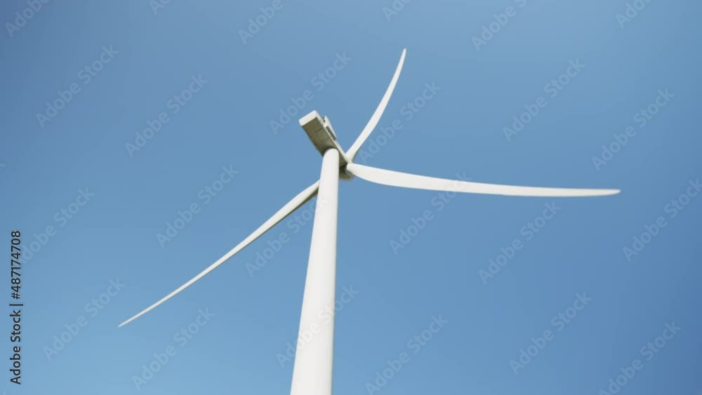 Close up of huge wind propeller working constantly on eco farm over blue sky. Concept of electric power production and clean energy. Close up of wind propeller working on field over blue sky. Close up of huge wind propeller working constantly on eco farm over blue sky. Concept of electric power production and clean energy. Close up of wind propeller working on field over blue sky.