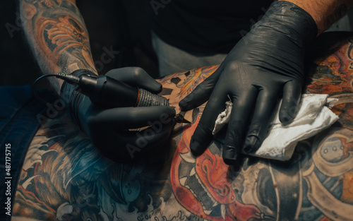 Hands of a tattoo artist holding a machine while working photo
