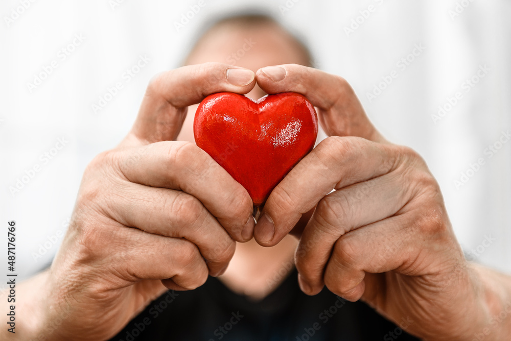 Red heart in a man's hand close-up. Red heart in a man's hand close-up.