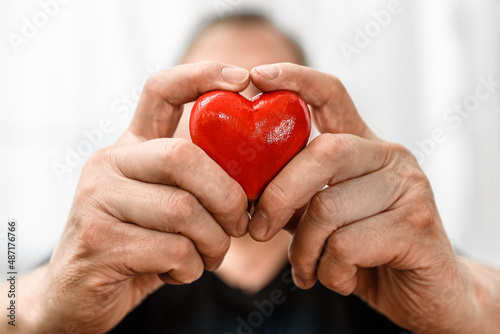 Fototapeta Naklejka Na Ścianę i Meble -  Red heart in a man's hand close-up.