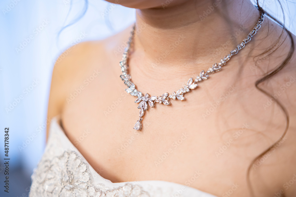 A beautiful diamond necklace is attached to the neck of the bride