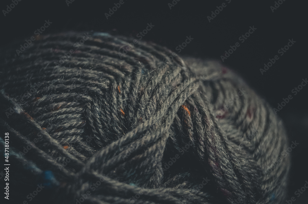 Close-up of a ball of tweed yarn on a black background. Natural yarn made of wool. Hand knitting. Hobby. Selective focus