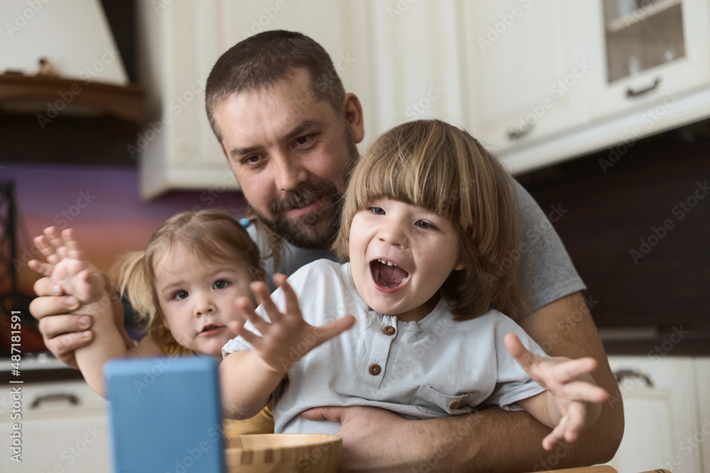 Father and the children are smiling and waving into the mobile phone Father and the children are smiling and waving into the mobile phone