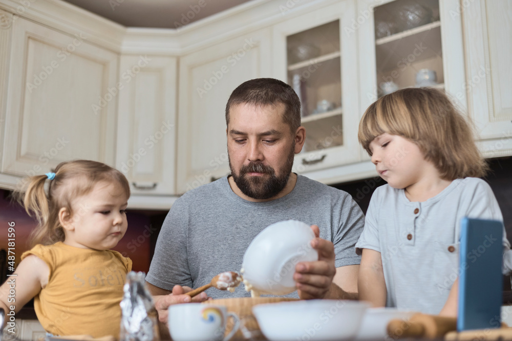 Father and two children prepare cookie dough Father and two children prepare cookie dough