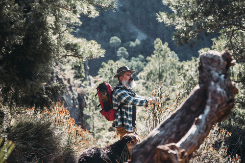 Bearded man hiking with his dog in the mountains.