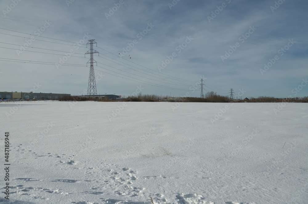 A Snow-Covered Wheatfield in Winter and Powerlines in the Background