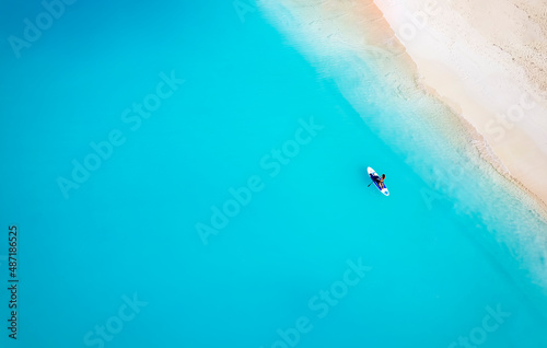 Fototapeta Aerial top down view of a woman on a stand up paddle (SUP) board over turquoise