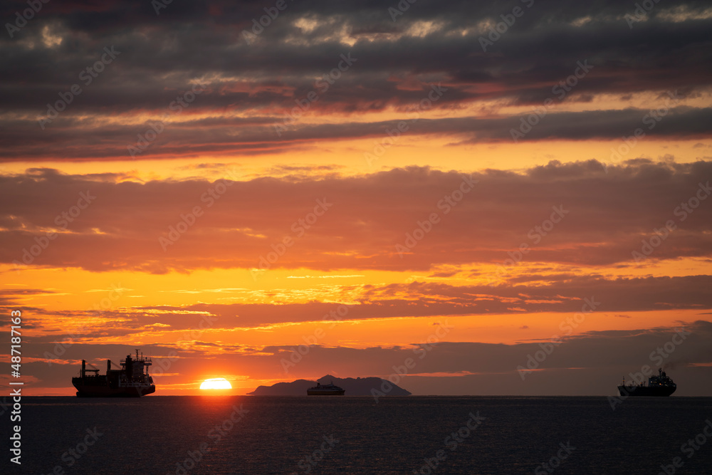 Fantastic sunset with ships an island and three ships in the backlight
