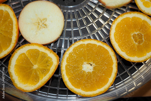 thin slices of oranges and apples lie on a plastic dryer preparing for christmas