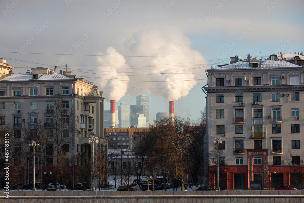 Environmental problem of environmental pollution and air in large cities. View of smoke from pipes between houses in the city