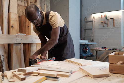 Fotografia Portrait of mature black man building wooden furniture in carpentry workshop, co