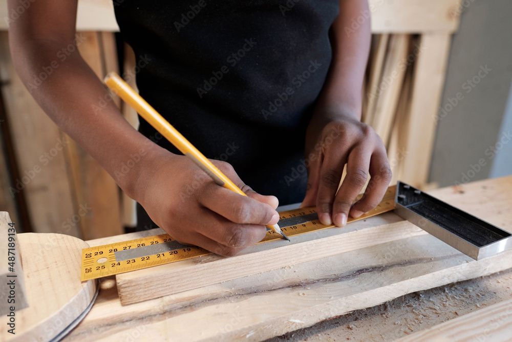 Close up of African-American boy measuring piece of wood in carpentry workshop, copy space Close up of African-American boy measuring piece of wood in carpentry workshop, copy space