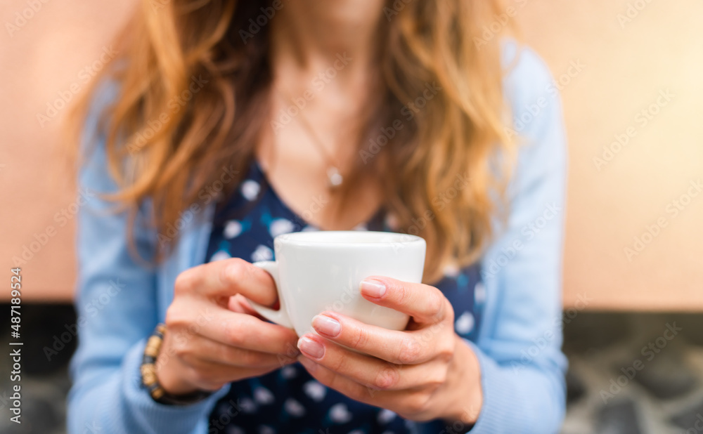 Woman's hands hold a cup of flavored coffee sitting in a street cafe on a summer day. Close-up. Woman's hands hold a cup of flavored coffee sitting in a street cafe on a summer day. Close-up.