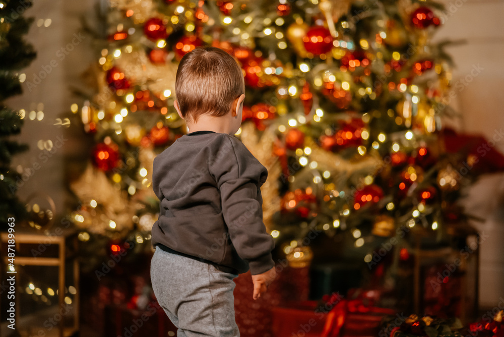 Little boy playing by the christmas tree